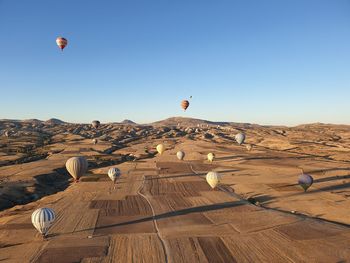 Hot air balloon flying over landscape against clear blue sky