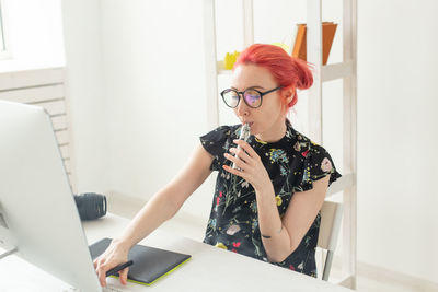 Young woman using phone while sitting on table