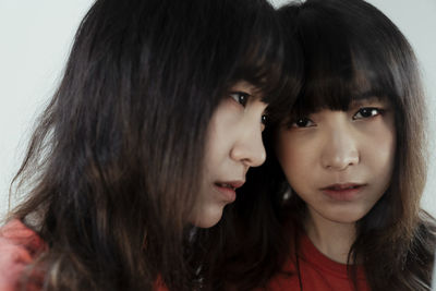 Close-up portrait of young woman standing by mirror