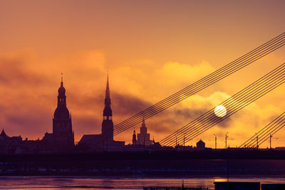 A beautiful riga cityscape with suspension bridge over the river during colorful sunrise. 