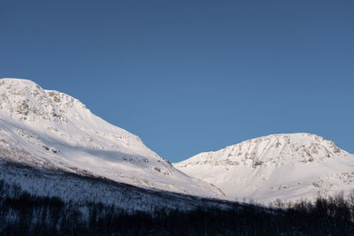 Snow covered mountain in northern norway on blue sky background.