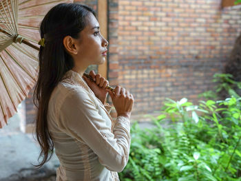 Side view of young woman looking away outdoors