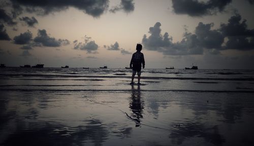 Silhouette man standing on beach against sky during sunset