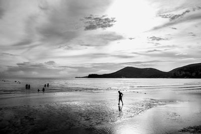 Silhouette man walking at beach against sky