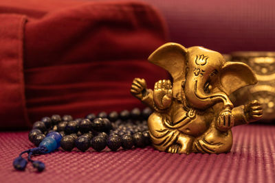 Close up of golden statue of ganesha on yoga mat with blue prayer beads and yoga pillow