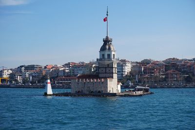 Sailboats in sea against buildings in city