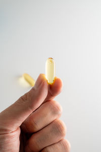 Close-up of hand holding wineglass against white background