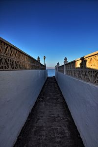 Surface level of bridge against clear blue sky