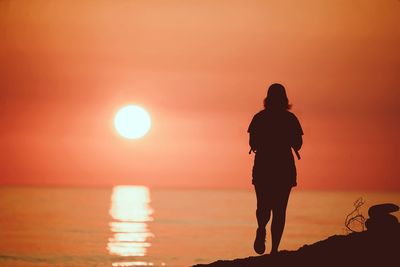 Silhouette people standing on beach during sunset