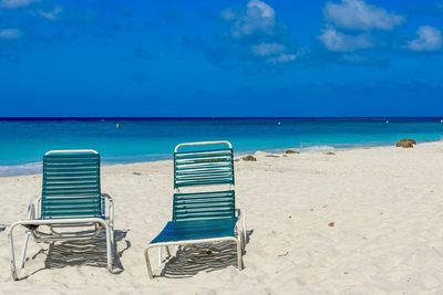 Chairs on beach against blue sky