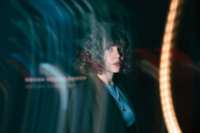 Portrait of young woman standing against black background