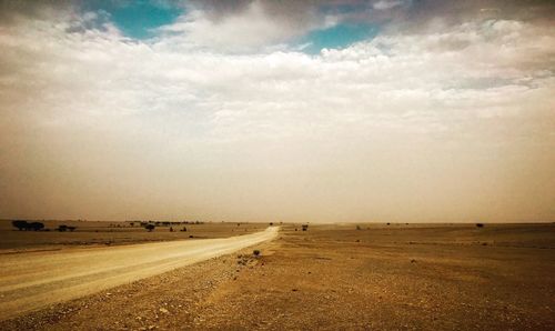 Road by field against sky