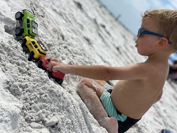 Side view of a boy sitting on beach