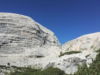 Low angle view of rocky mountains against clear blue sky