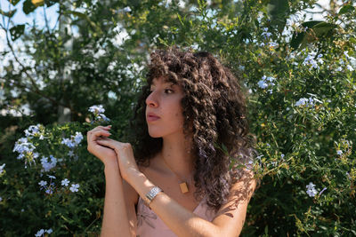 Portrait of young woman holding flower in tree