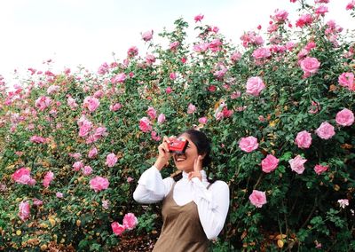 Woman standing by pink flowering plants