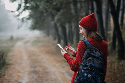 Travel apps. young woman traveler with backpack holding smartphone device in hands
