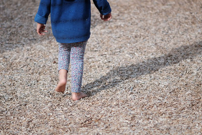 Rear view of girl walking on wood chips