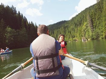 Rear view of father and daughter on boat sailing in river