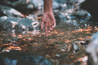 Cropped hand touching water flowing in stream