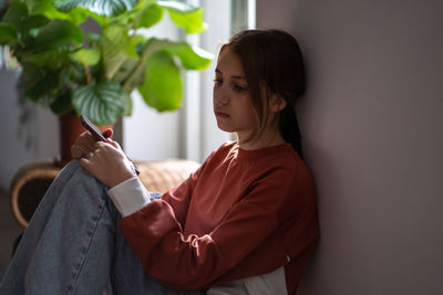 Portrait of young woman standing against wall