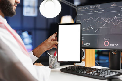 Midsection of man using digital tablet in office