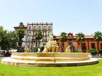 Fountain in front of building against clear sky
