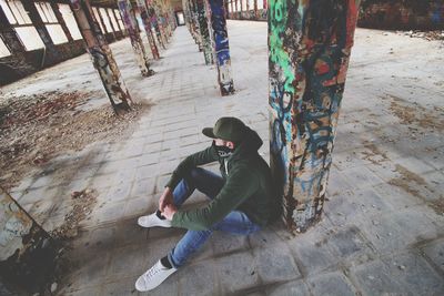 Man in hood clothing sitting in abandoned room