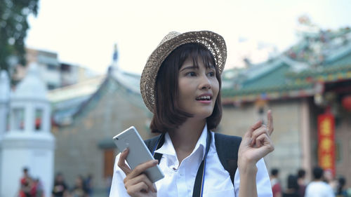 Portrait of smiling woman holding smart phone in city