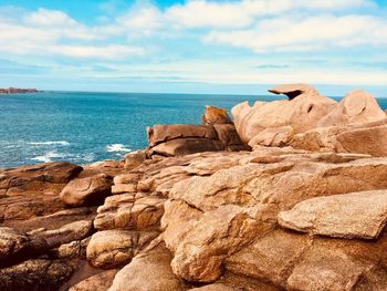 Rock formations on beach against sky