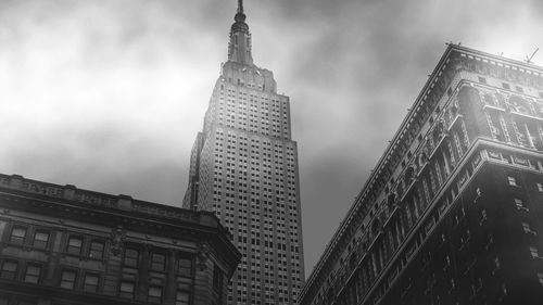 Low angle view of buildings against cloudy sky in city