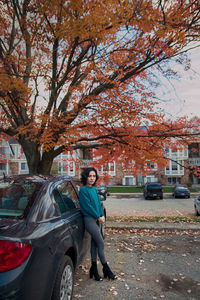 Portrait of woman standing by car during autumn