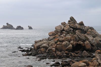 Rock formation on beach against sky