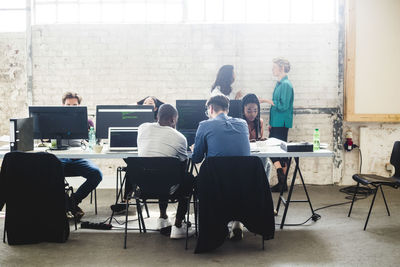 Young computer programmers coding at desk in creative office