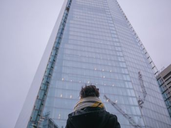 Rear view of woman standing against modern building