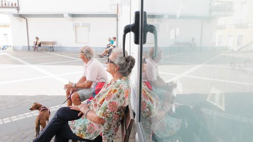 Senior people with dog sitting on bench at city street