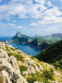 Scenic view of sea by mountains against sky