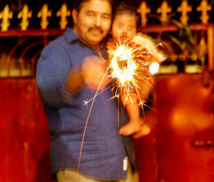 Midsection of man holding sparkler at night