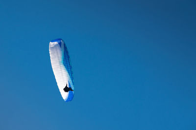 Low angle view of airplane flying against clear blue sky