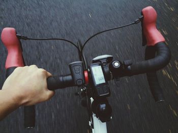 Cropped hand riding bicycle on road