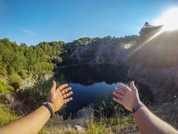 Cropped image of hand by tree against sky