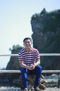 Portrait of smiling young man sitting on rock