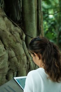 Rear view of woman using digital tablet in forest