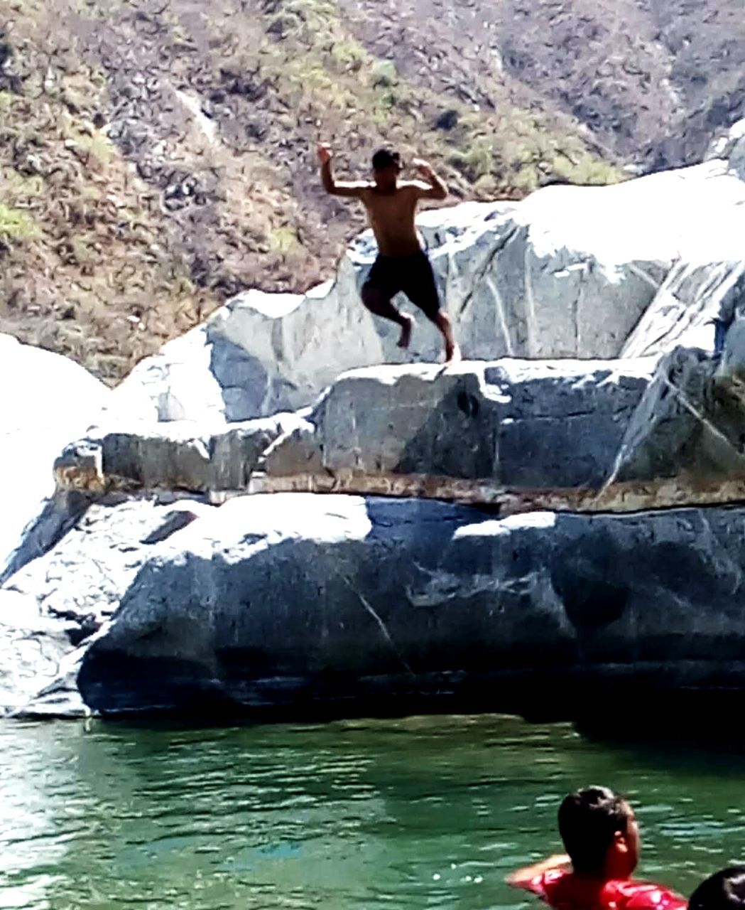 real people, water, rock, leisure activity, rock - object, lifestyles, one person, solid, day, nature, waterfront, young adult, river, beauty in nature, full length, rock formation, outdoors, adult