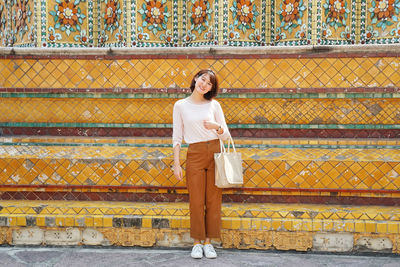 Portrait of woman standing against wall