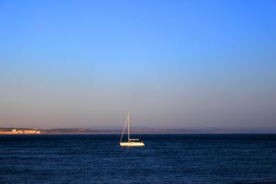 Sailboat sailing on sea against clear sky