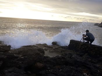 Full length of man photographing waves