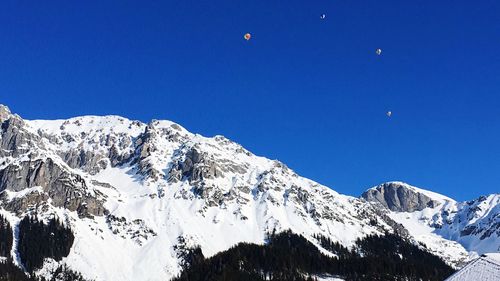 Low angle view of snowcapped mountains against clear blue sky