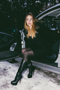 Full length of young woman sitting in car during winter