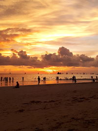 Silhouette people on beach against sky during sunset